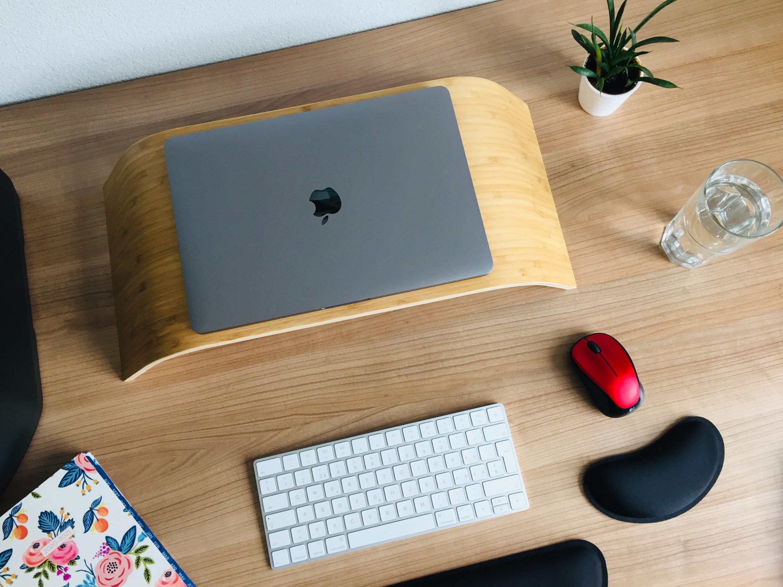 Ergonomischer Arbeitsplatz: Ein Laptop auf einer erhöhtem Bank. Davor Tastatur und Maus mit Handgelenks-Stützen.